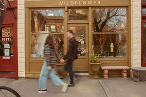 Storefront views of Wildeflower shop with wood paneling and large windows displaying floral arrangements and decor.