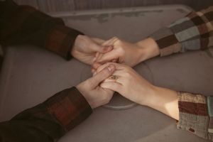 Two people holding hands intimately during a table conversation at a coffee shop or cafe.