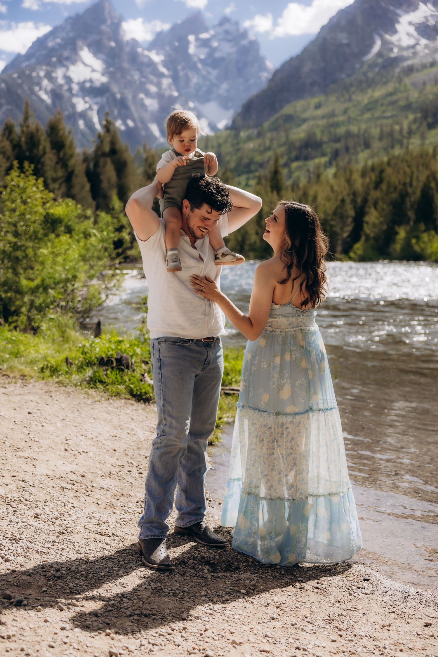A scenic mountain view provides backdrop for a family enjoying a moment together by a river.