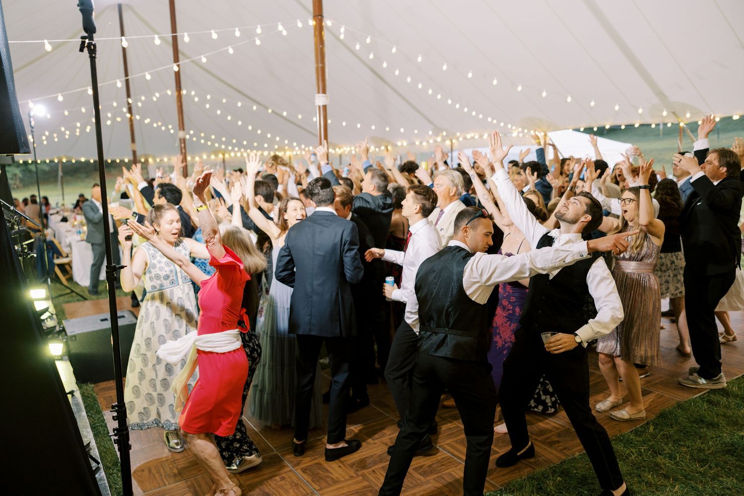 Elegant wedding reception venue with tall floral centerpieces, black chiavari chairs, and white table settings in bright space.