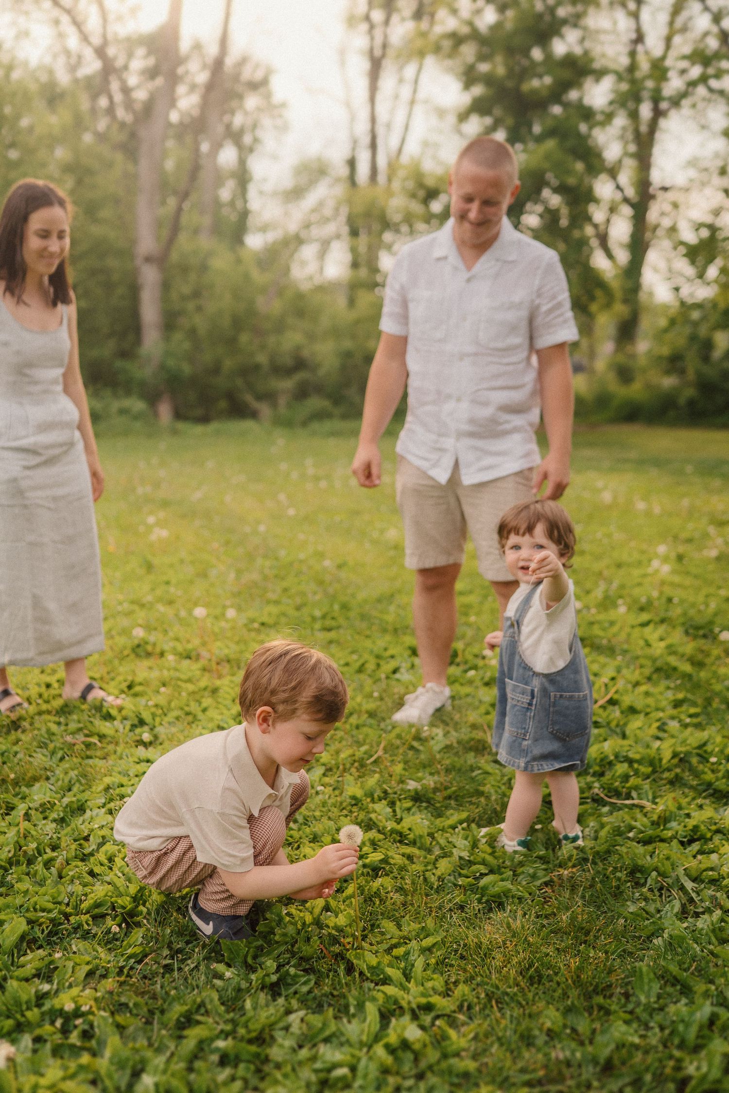 A family spends quality time together outdoors in a lush green field on a sunny summer evening.