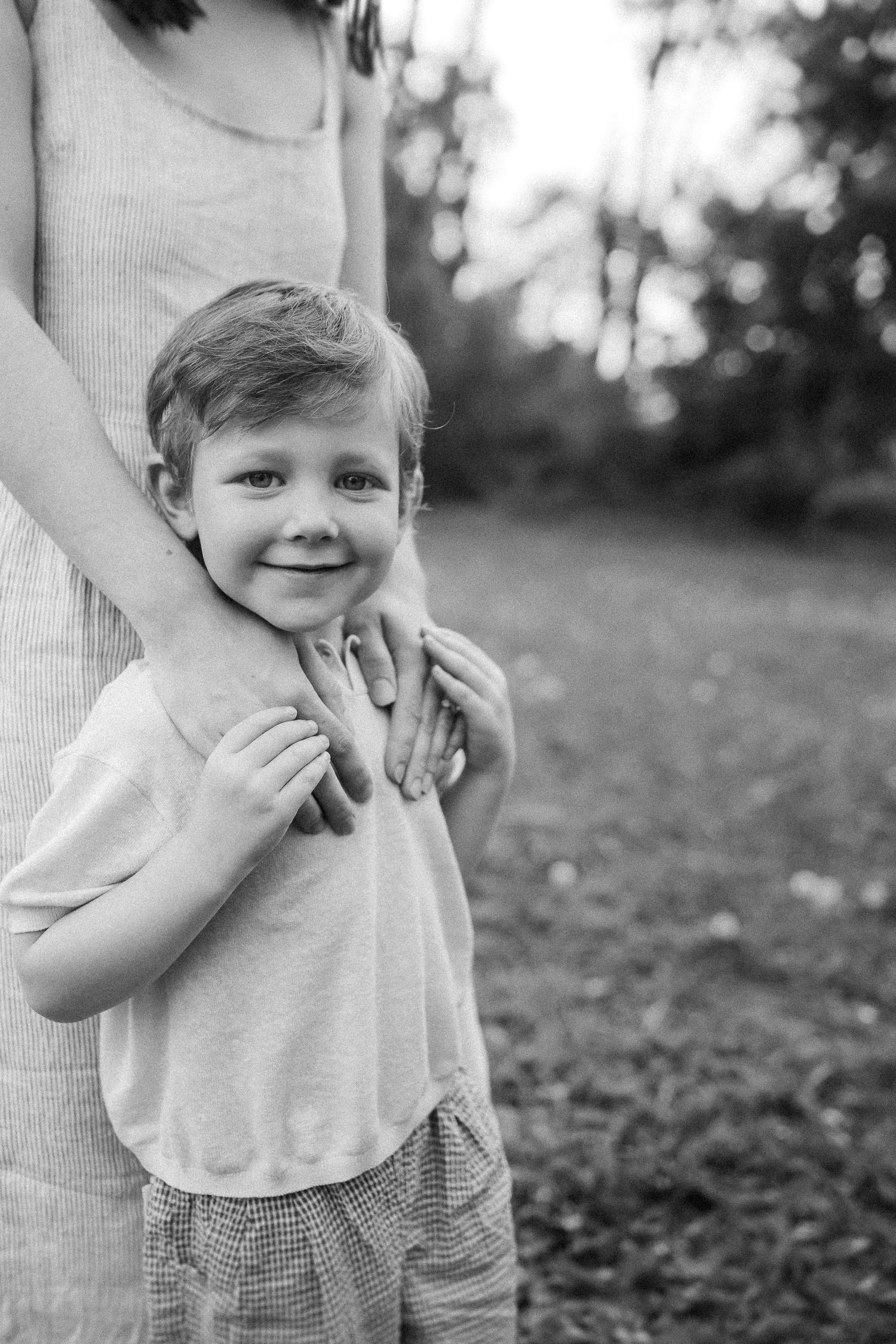 Black and white images show a child in a light-colored shirt standing outdoors among leaves and grass.
