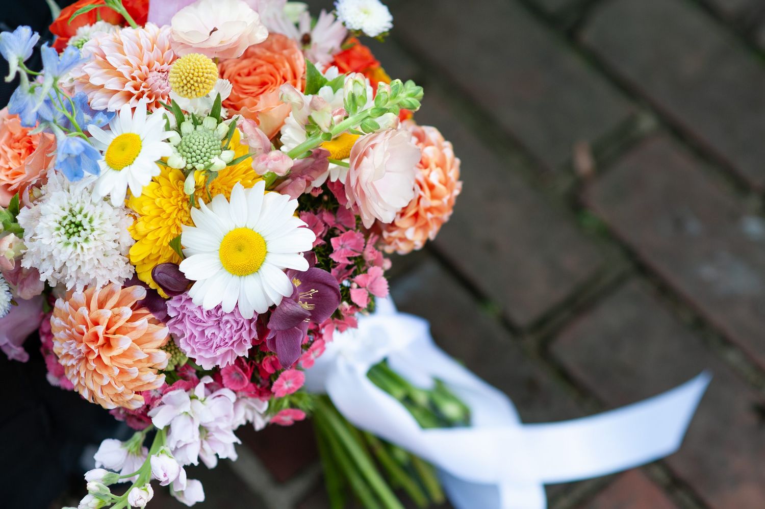 Vibrant wedding bouquet with colorful daisies, roses and mixed flowers.