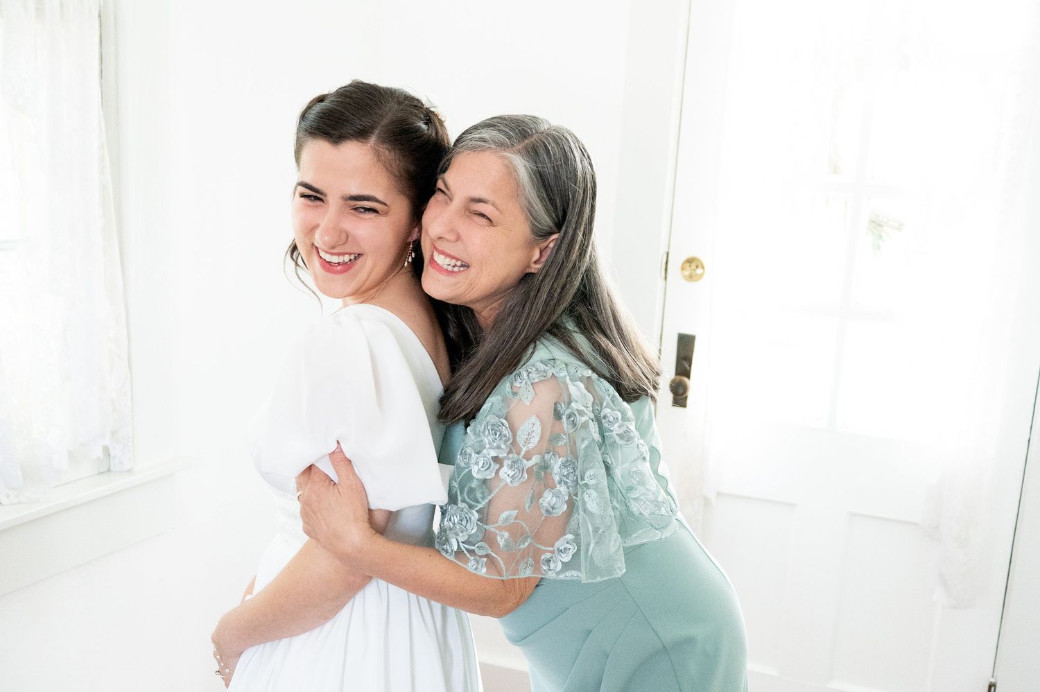 Two people share joyful moments in a bright white room.
