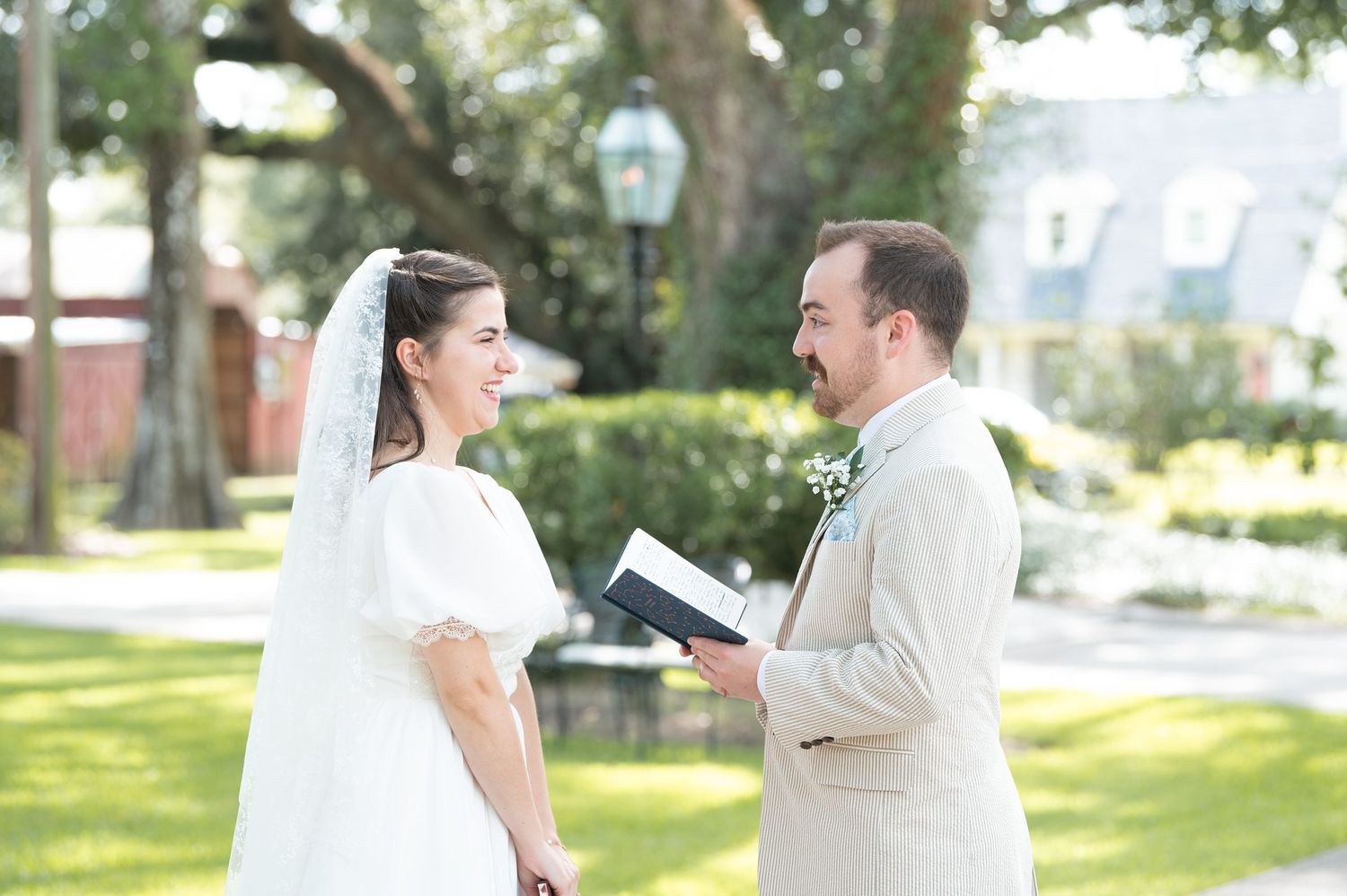 An outdoor wedding ceremony with participants in formal white attire.