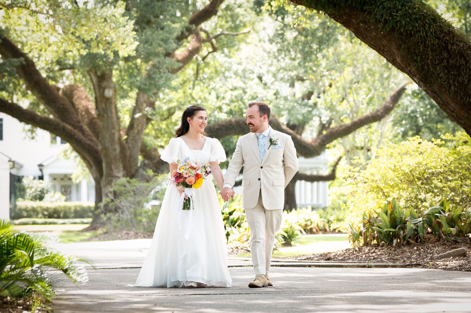 A wedding party arranged under the sweeping branches of a majestic oak tree.