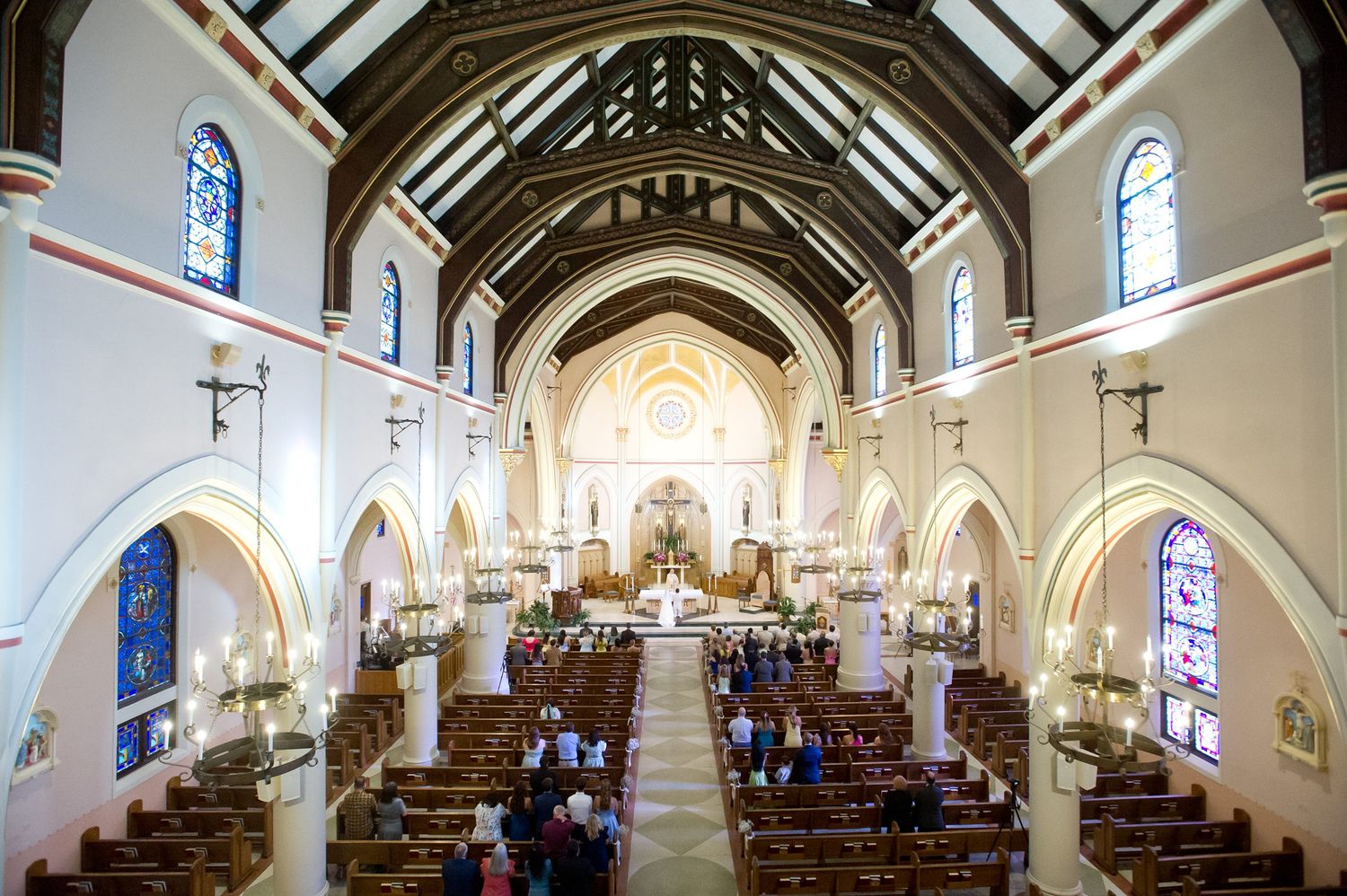 Aerial view of a Gothic church interior with vaulted ceilings and stained glass windows during a ceremony.