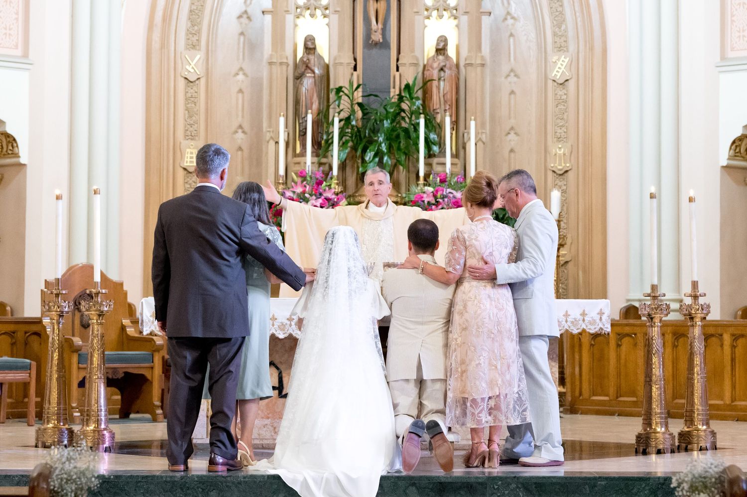 Wedding ceremony taking place at the altar of an ornate Catholic church.