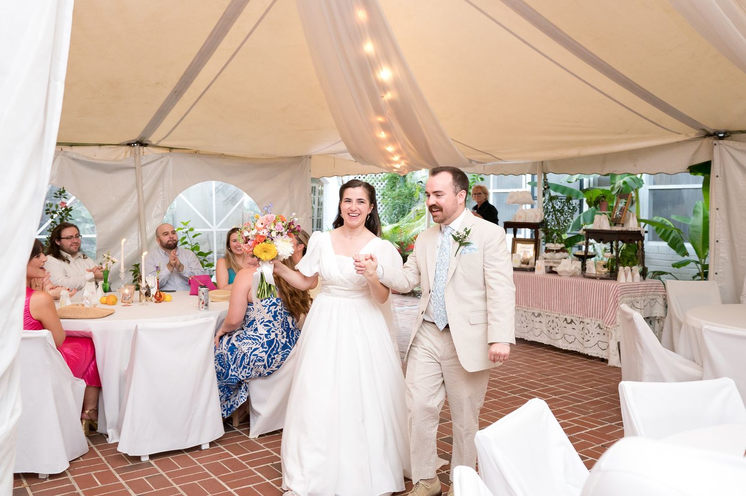Wedding reception setup with white tablecloths and decorations in an indoor venue.