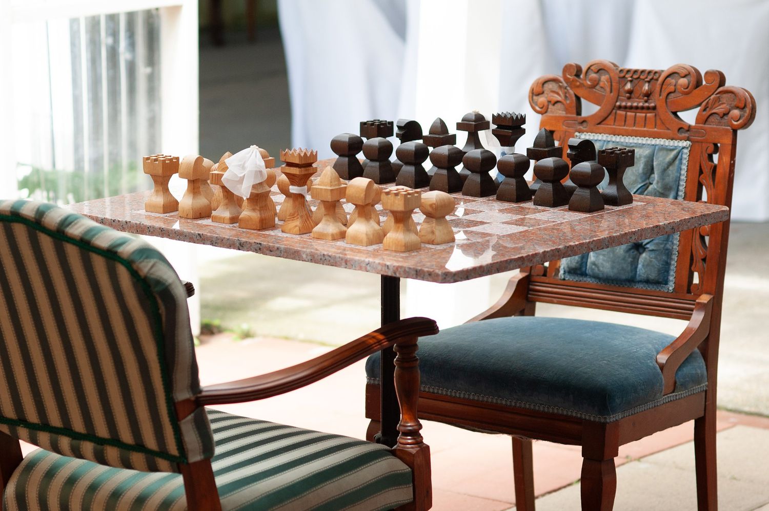 Ornate wooden chairs and furniture arranged in an elegant indoor setting.