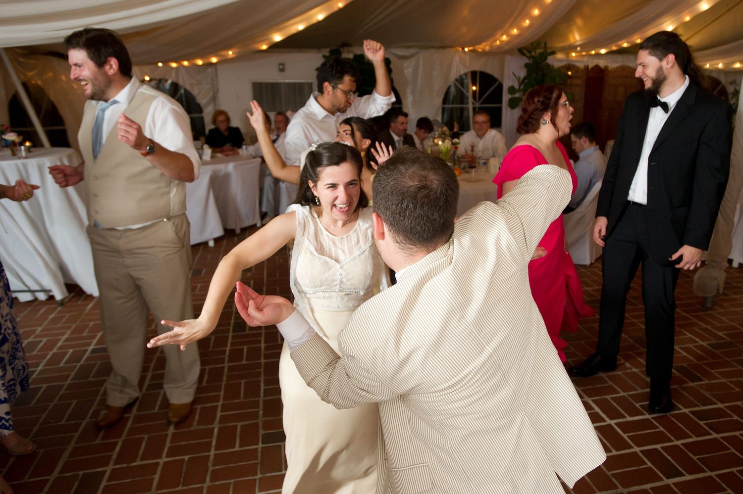 Energetic dance party with guests celebrating on a brown tiled dance floor.