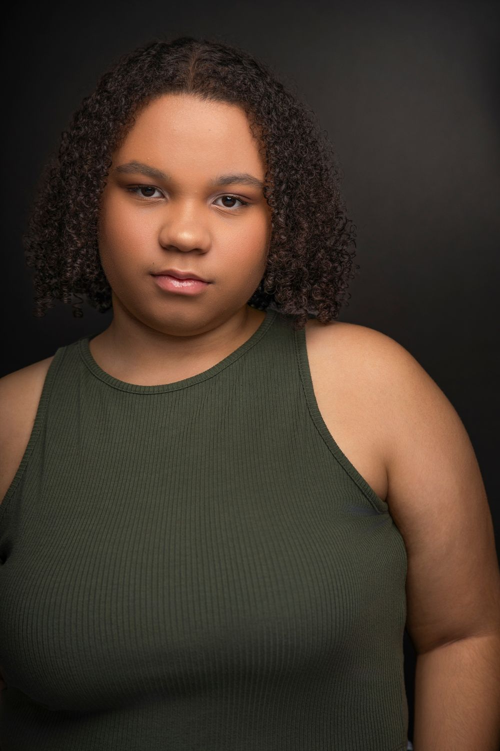A series of dramatic portrait photos featuring someone wearing an olive green tank top against a dark background.