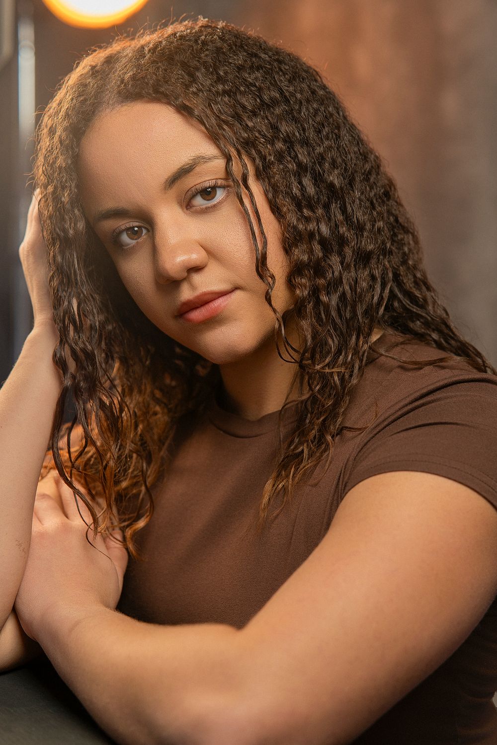 A series of artistic portrait photographs showing warm lighting and curly hair against a dark background.