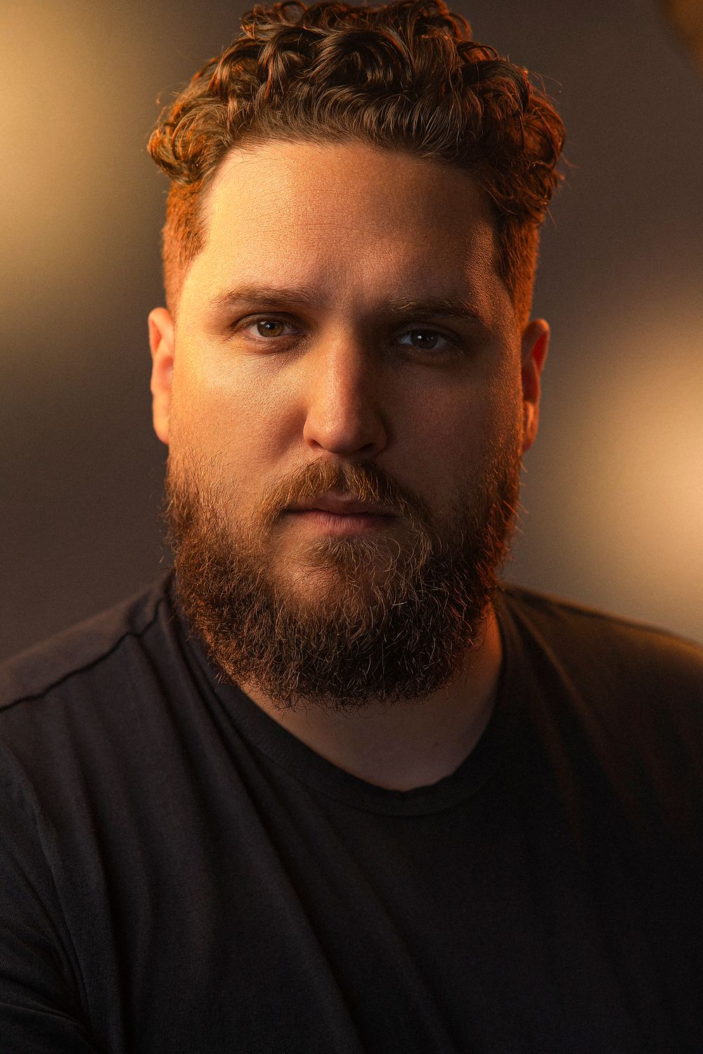 Portrait photo series showing a bearded person in a black shirt against a dark background with warm lighting.