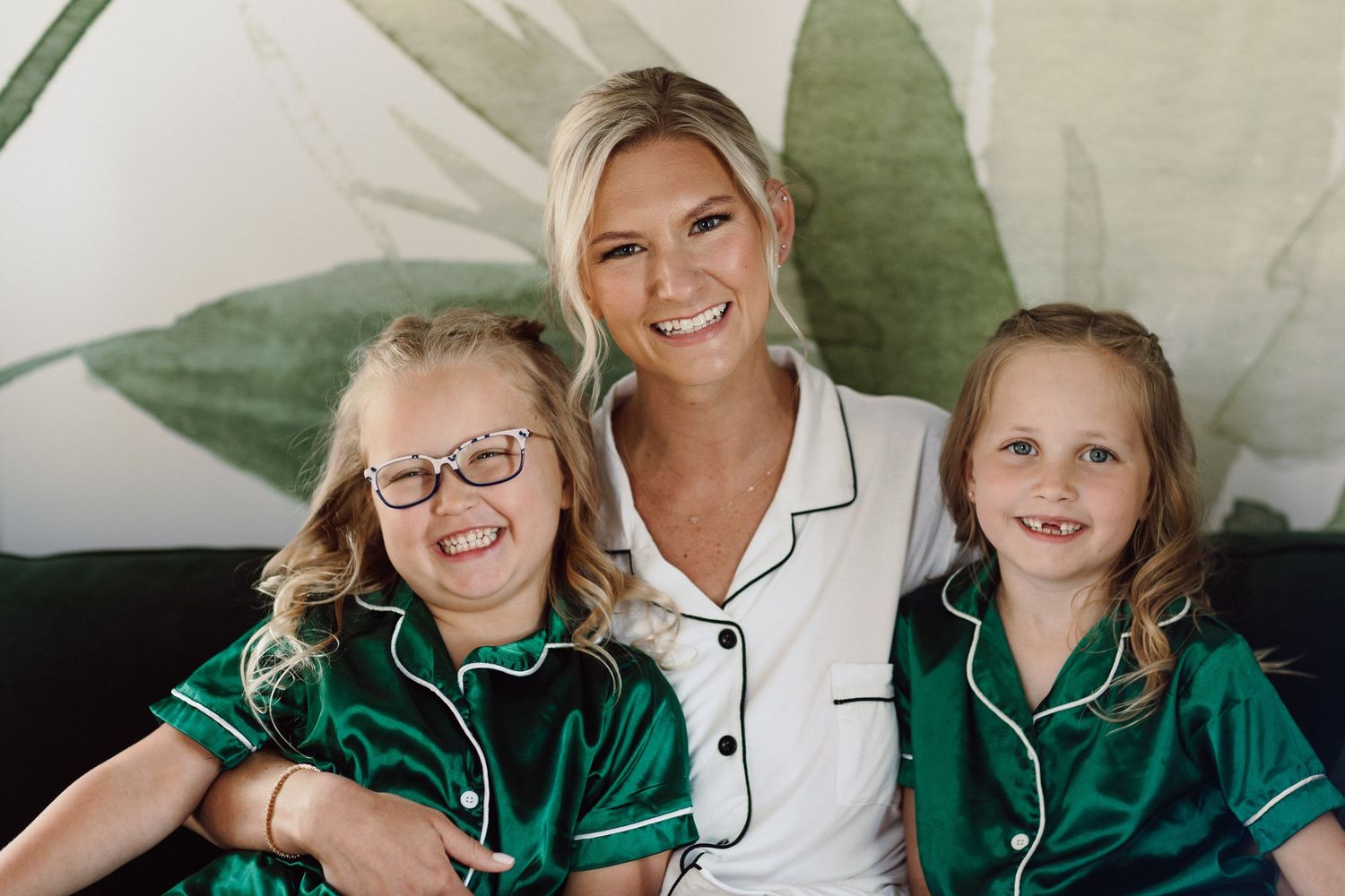 Family members wearing matching green and white pajamas share loving moments together.