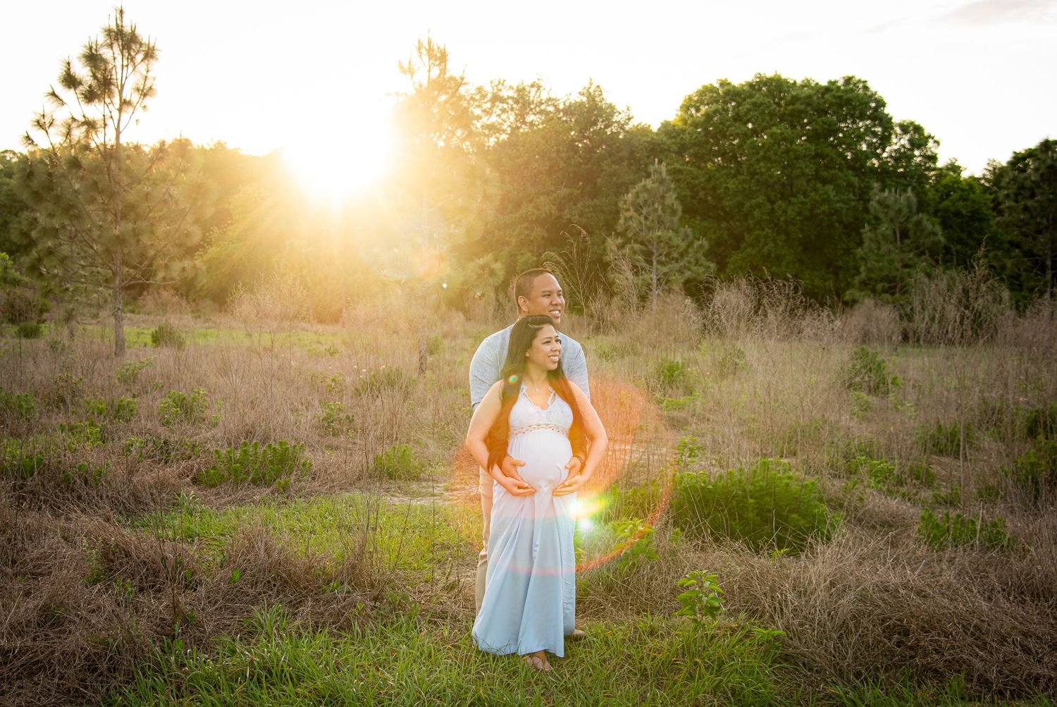 Sunset engagement photography session in a golden field with warm glowing sunlight and natural desert foliage.