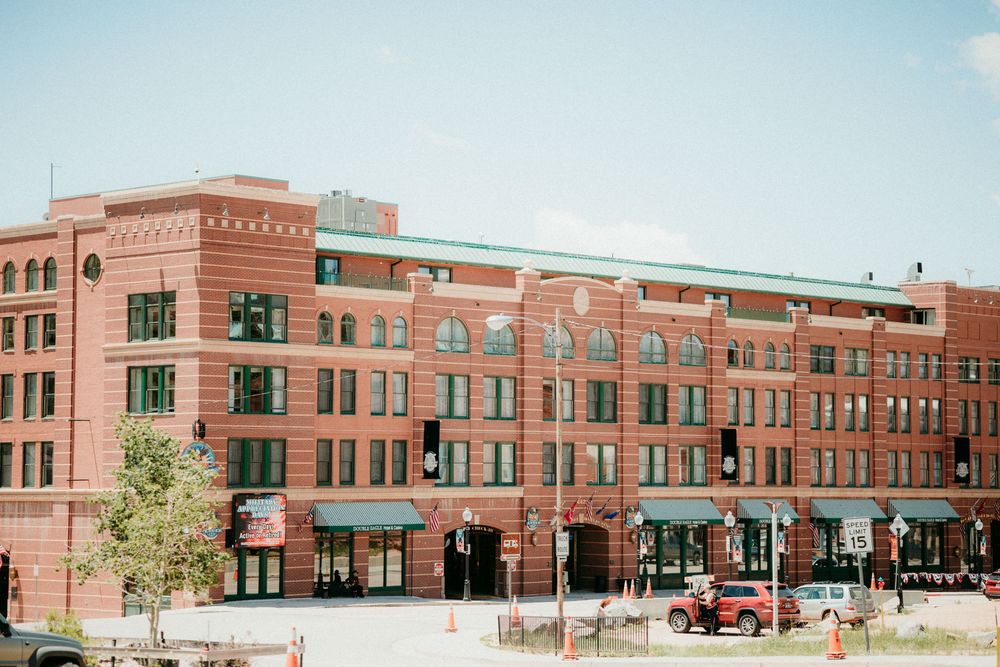 Historic red brick commercial building with retail storefronts and multiple stories in an urban setting.