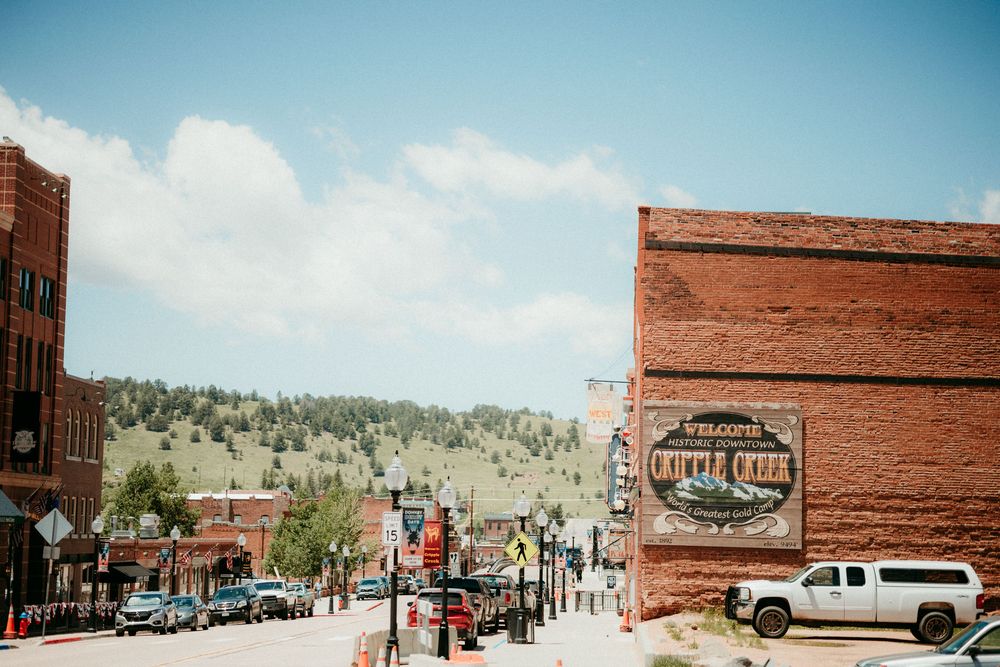 A scenic view of downtown Cripple Creek, Colorado with historic brick buildings and mountains in the background.