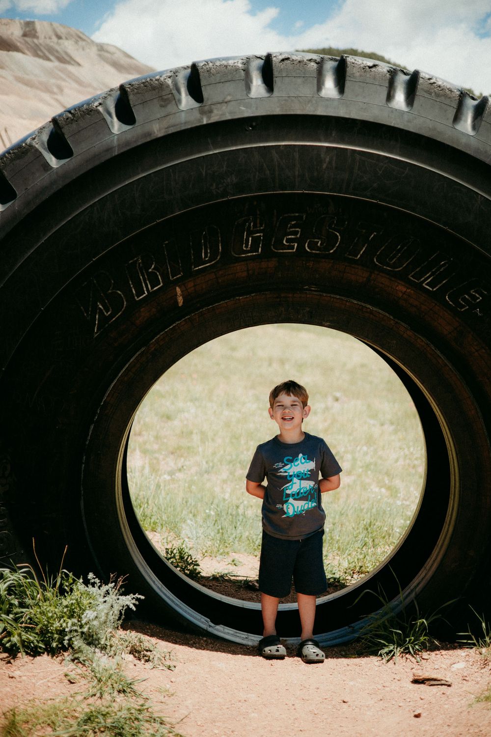 A creative sequence of linked photos showing a view through a large truck tire where figure appears in the frame progressively.
