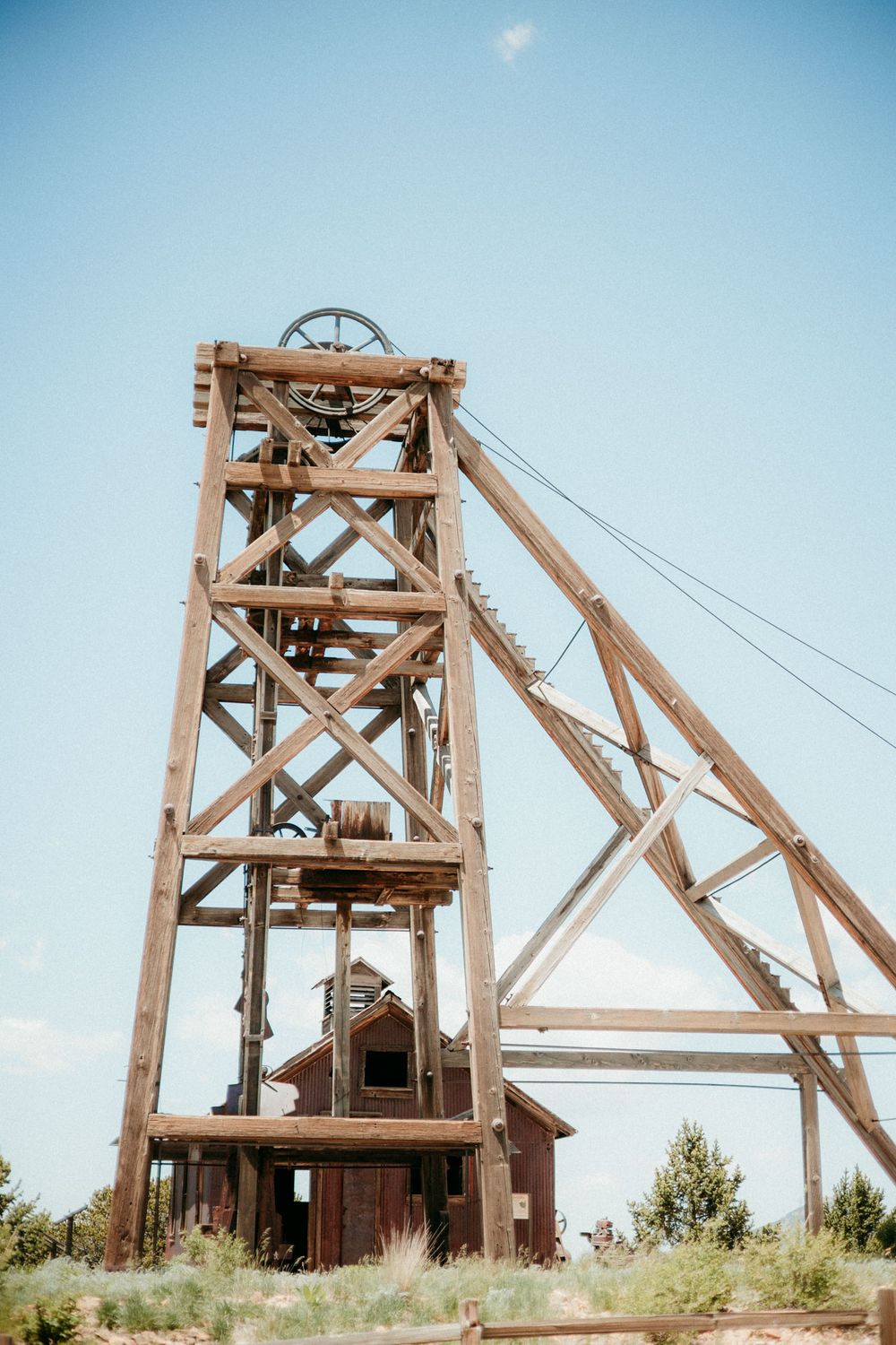 Wooden mining headframe structure from different angles against a blue sky in an abandoned mine site.