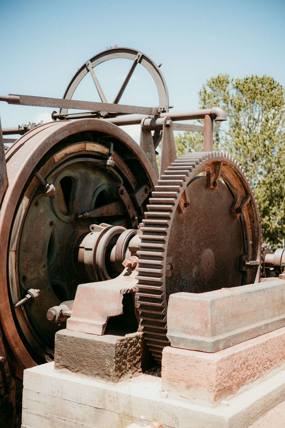 Close-up view of vintage industrial machinery showing large metal gear wheels and mechanical components outdoors.