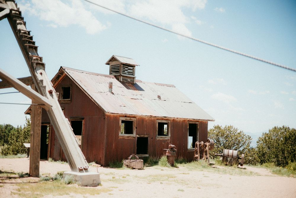 A panoramic view showing the progression of an old red barn collapsing in a rural field setting.