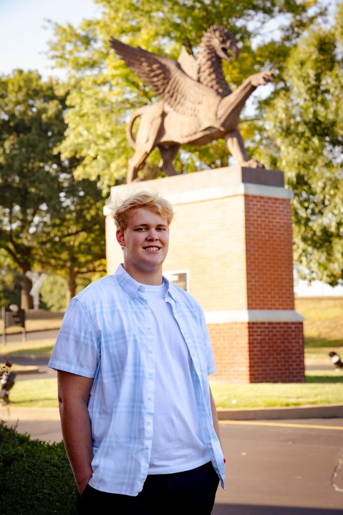 Senior portrait of a high school student standing in front of a staute.