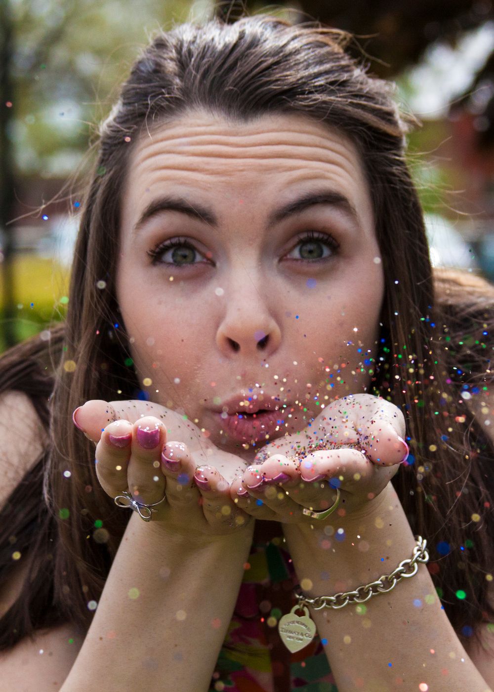 Senior portrait of high school girl blowing glitter off her hands.