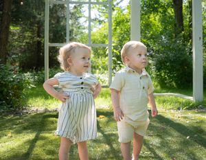 Children play and explore in a sunny outdoor garden setting with lush greenery in the background.