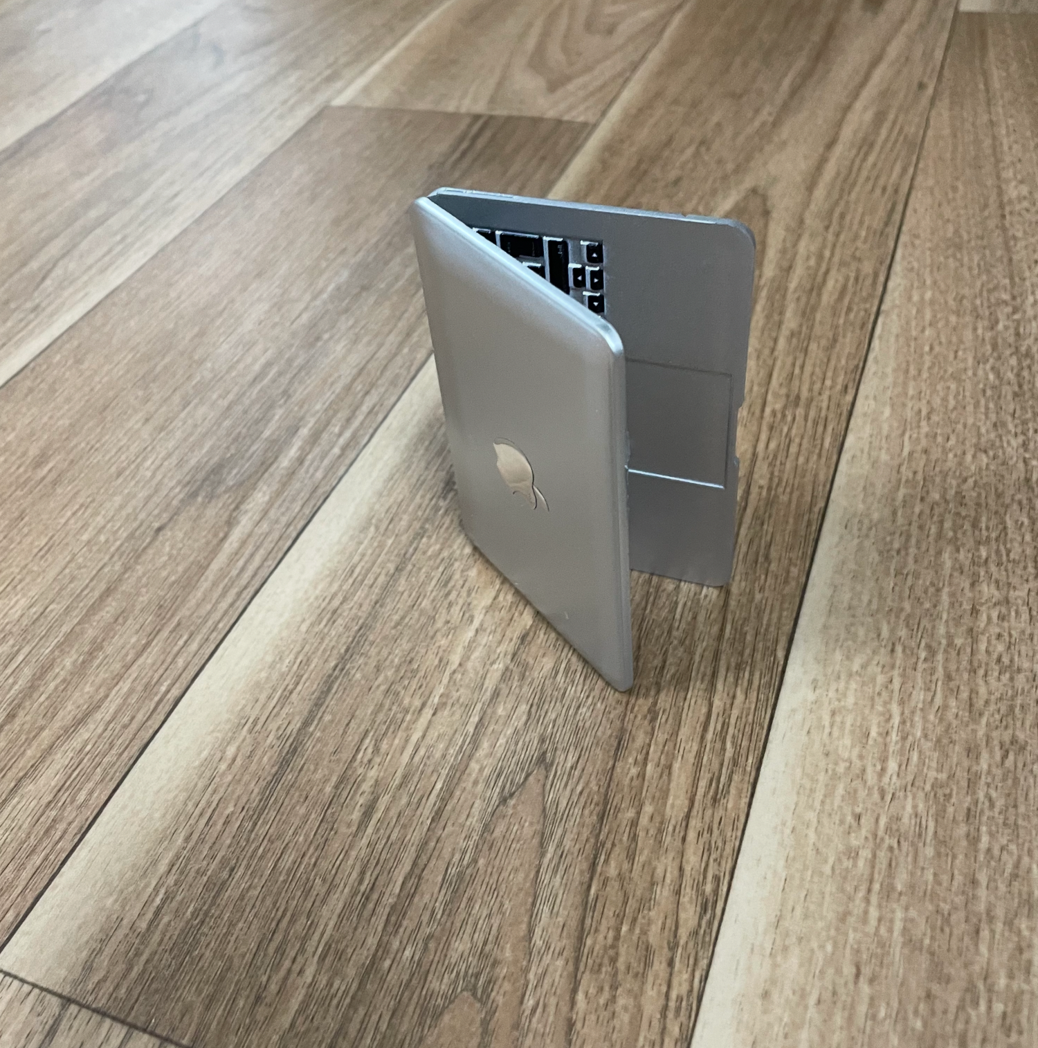 Gray laptop stand or holder shown at different angles on wooden floor.