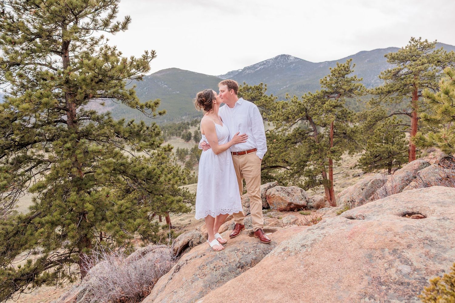 couple standing on rocky ledge at 3M Curve, sweeping mountain views in RMNP, dramatic Colorado elopement backdrop