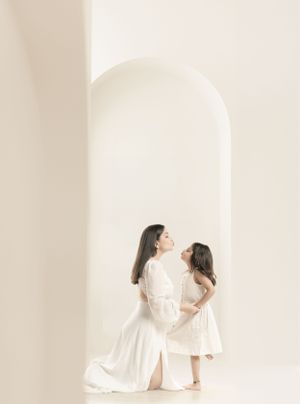 Elegant white-on-white portrait capturing intimate family moment under an archway.