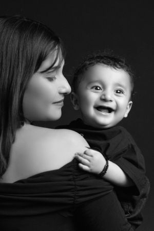 Sweet portrait of parent and baby against black background.