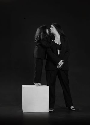 Artistic black and white portrait of two people in suits using white cube prop.