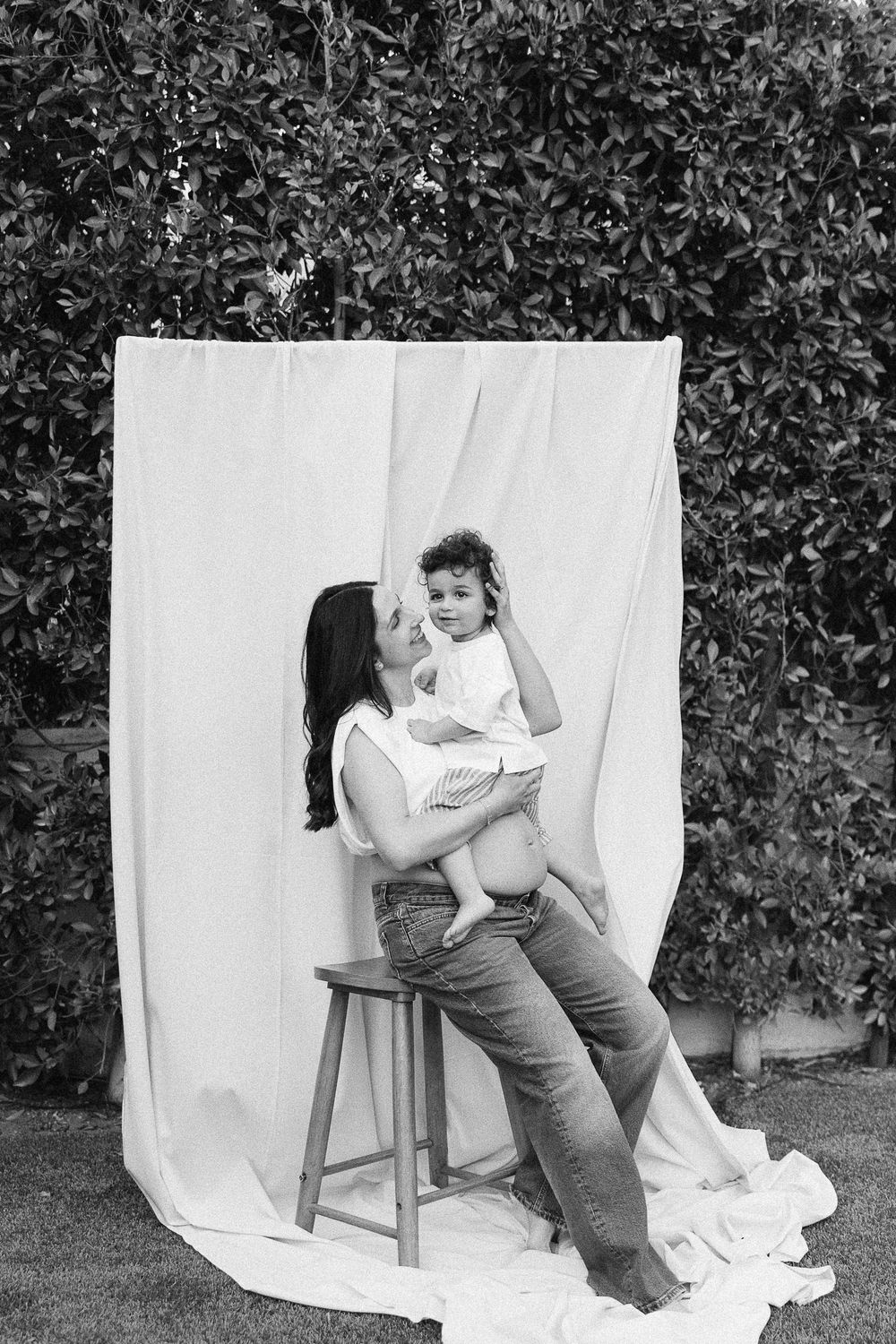Professional black and white photo series shows motion sequence of a small child tipping over sideways in a chair.