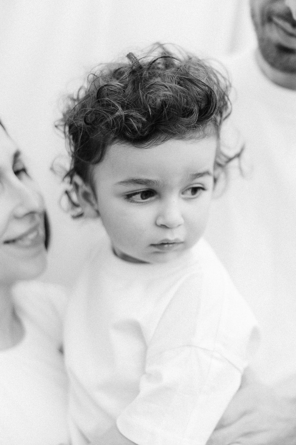 Black and white portrait of a young child with curly dark hair wearing a white shirt.