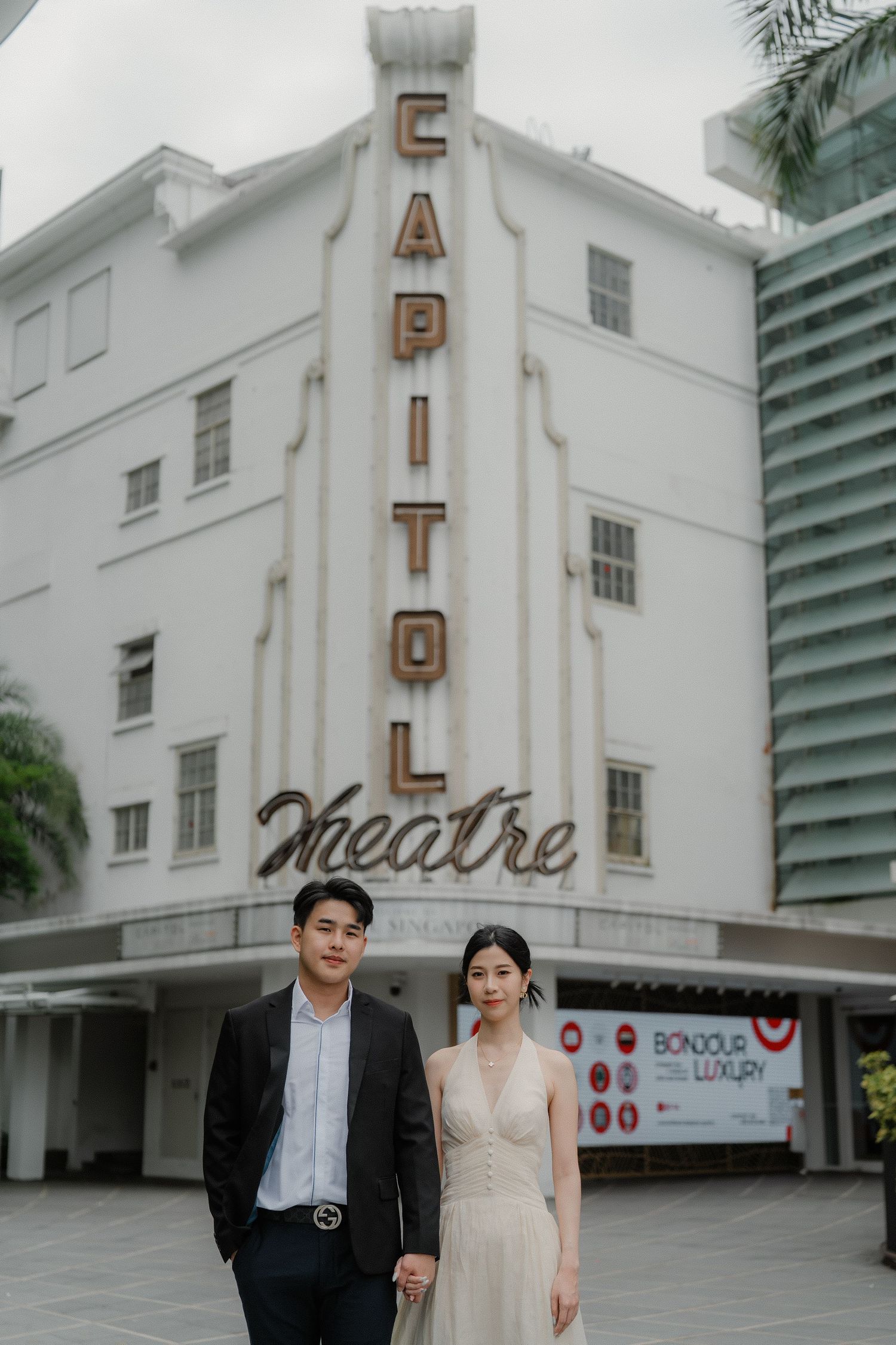 A couple strolls hand in hand outside the Capitol Theatre's classic white art deco architecture.