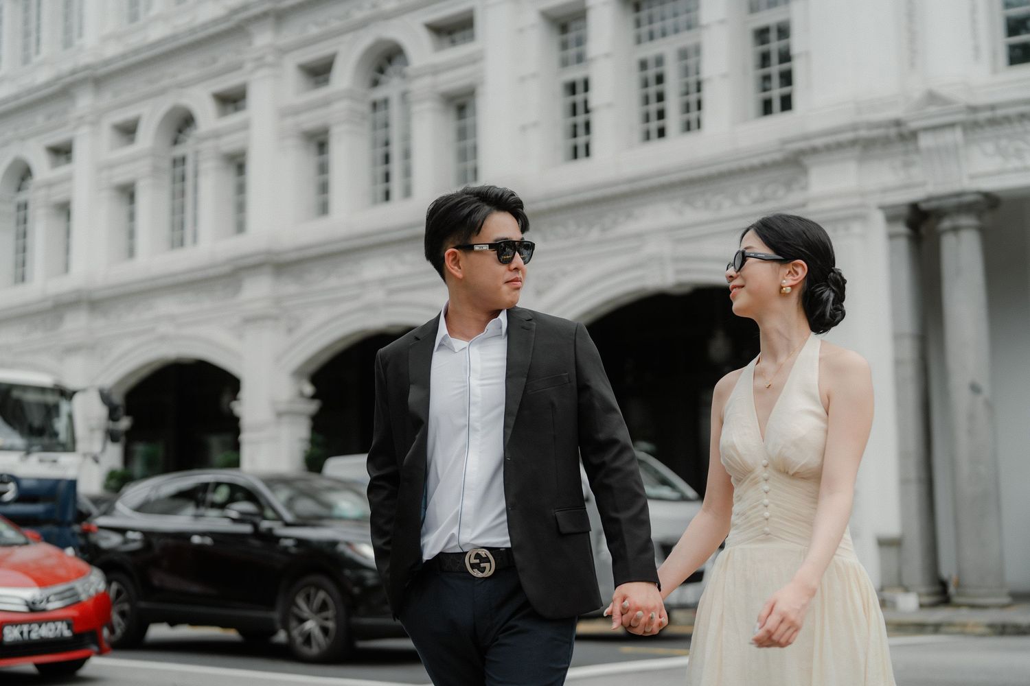 A well-dressed couple poses outside The Capitol Kempinski building.
