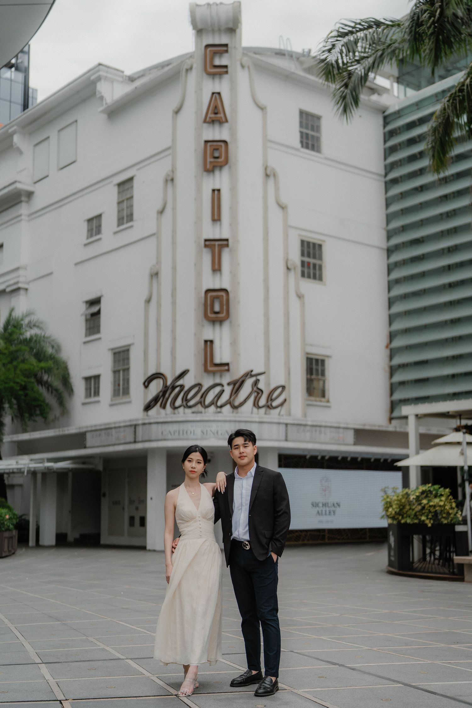 A couple poses in formal attire in front of the classic Capitol Theatre with its iconic vertical signage.