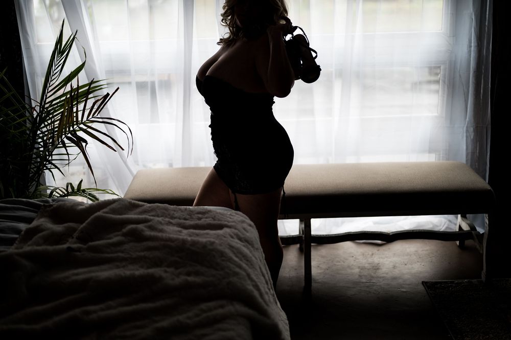 Moody silhouette portrait with window light and indoor plants.
