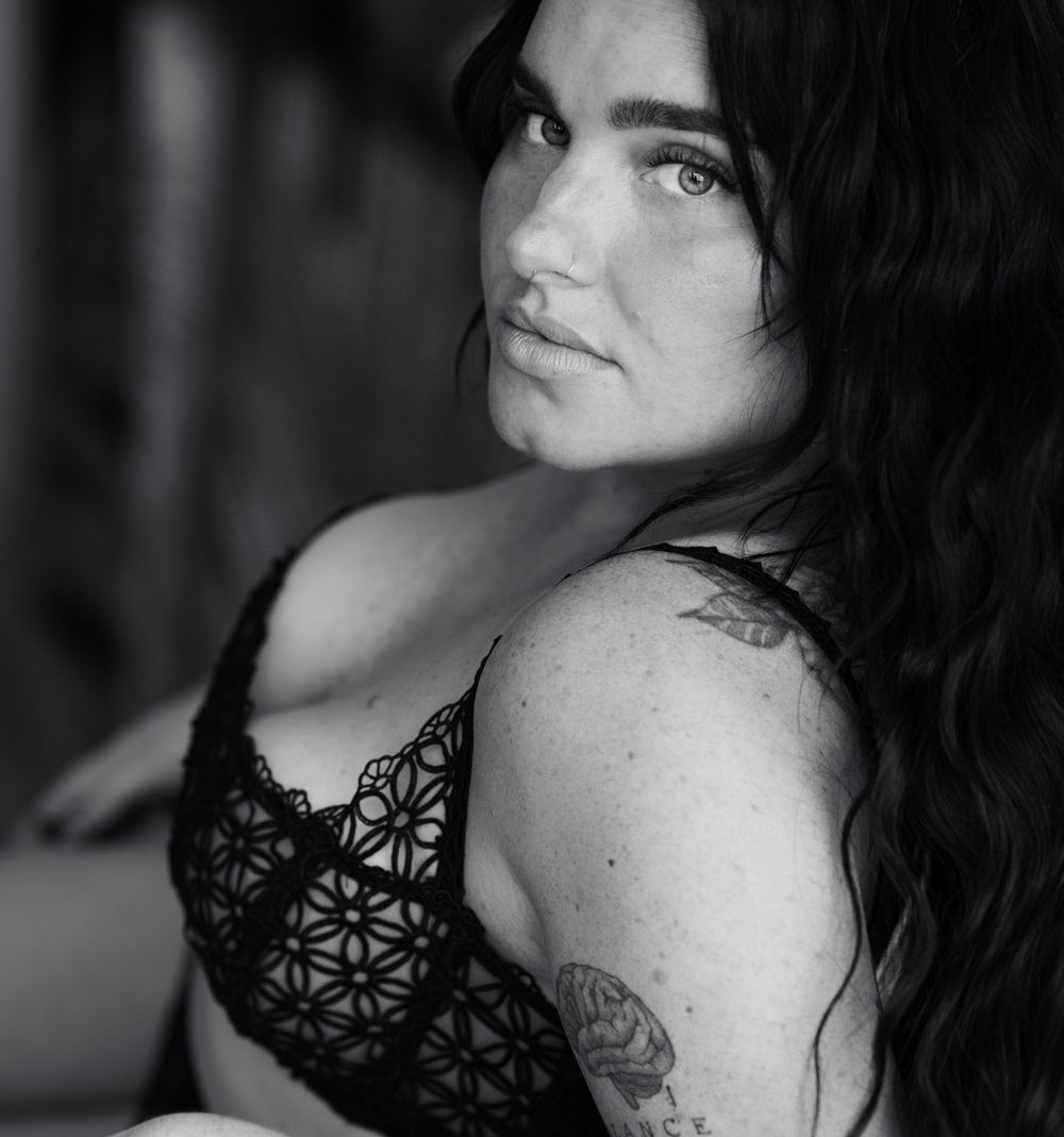 Black and white portrait featuring dark hair and lace details against a moody background.
