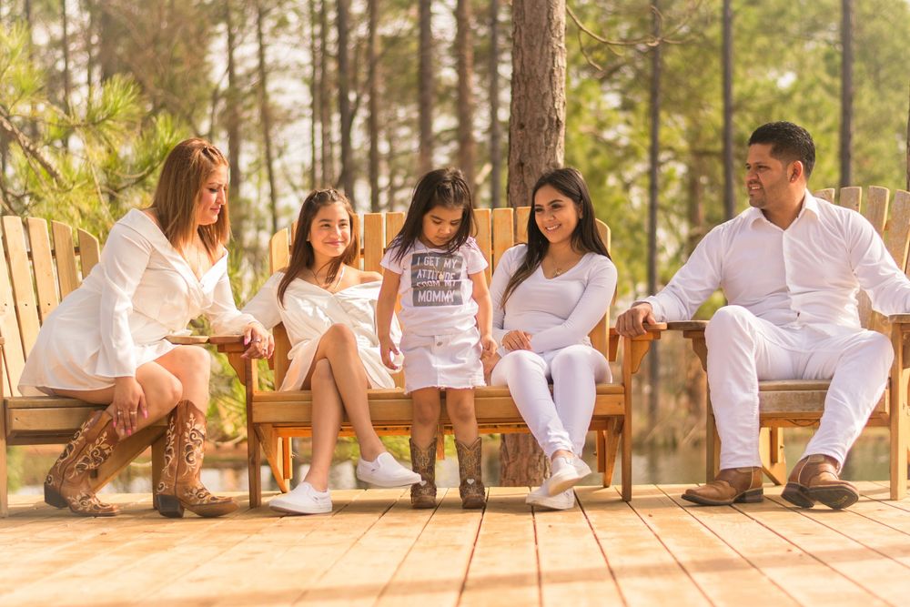 Group photo session of family members in white attire among pine trees.