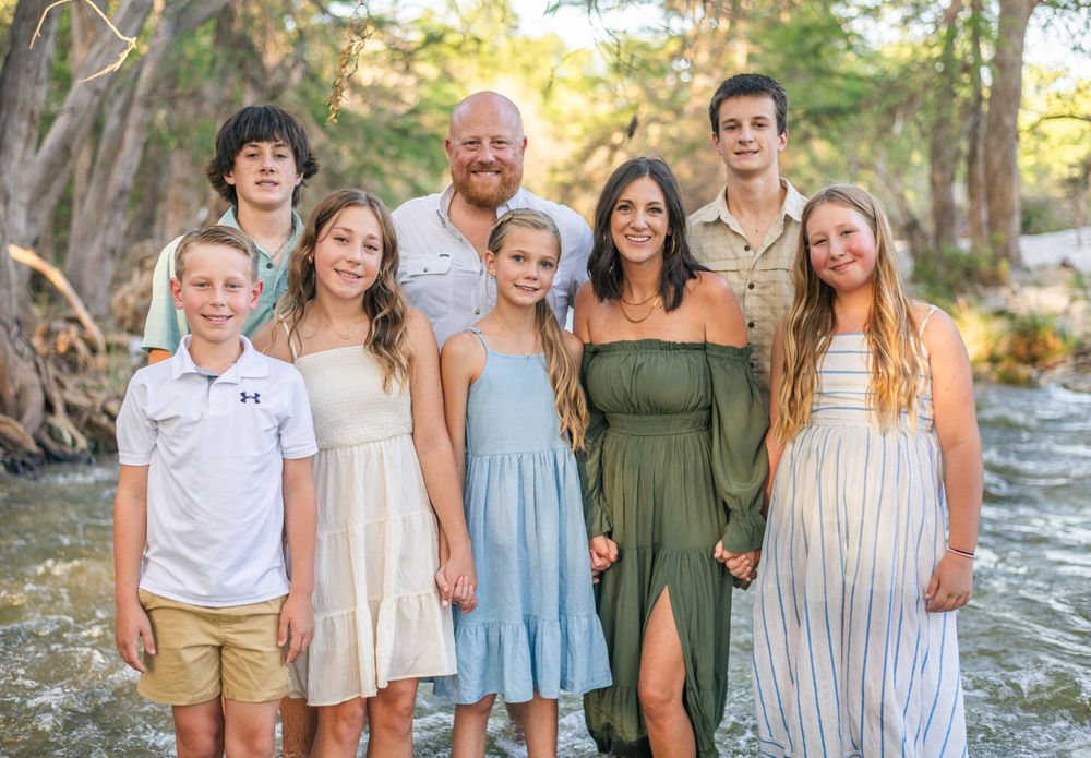 Large family group wearing coordinated outfits poses together outdoors.