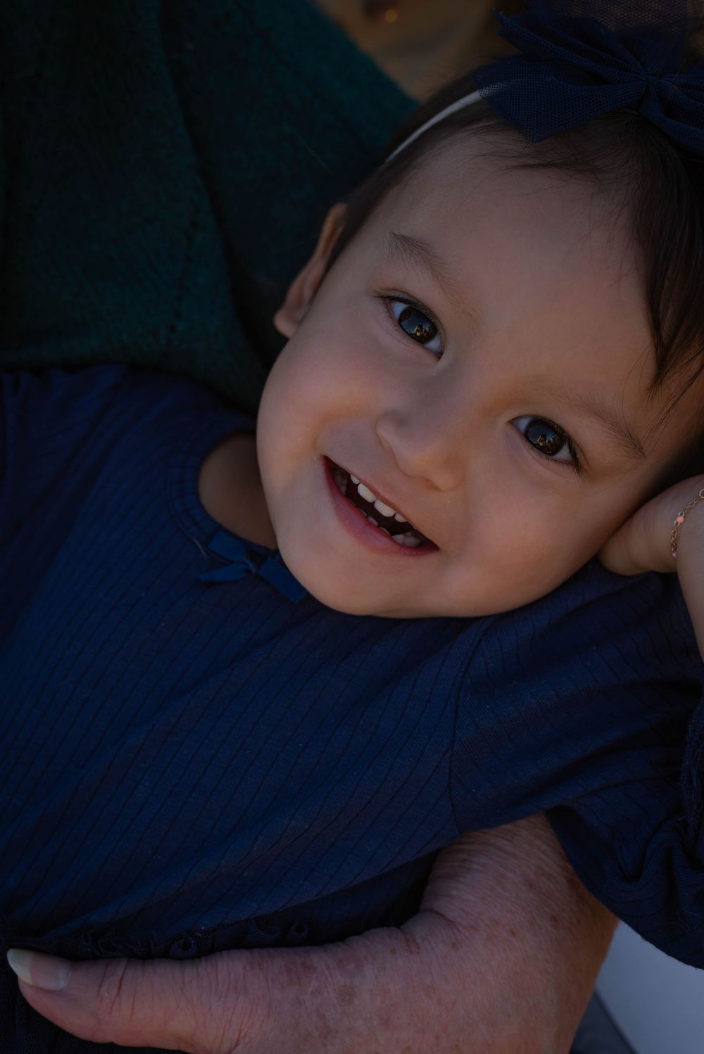 Child lying on dark blue fabric in low light conditions.
