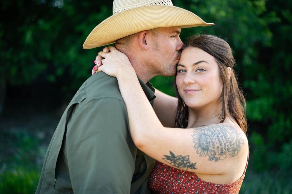 A couple embraces in a romantic outdoor setting during golden hour.