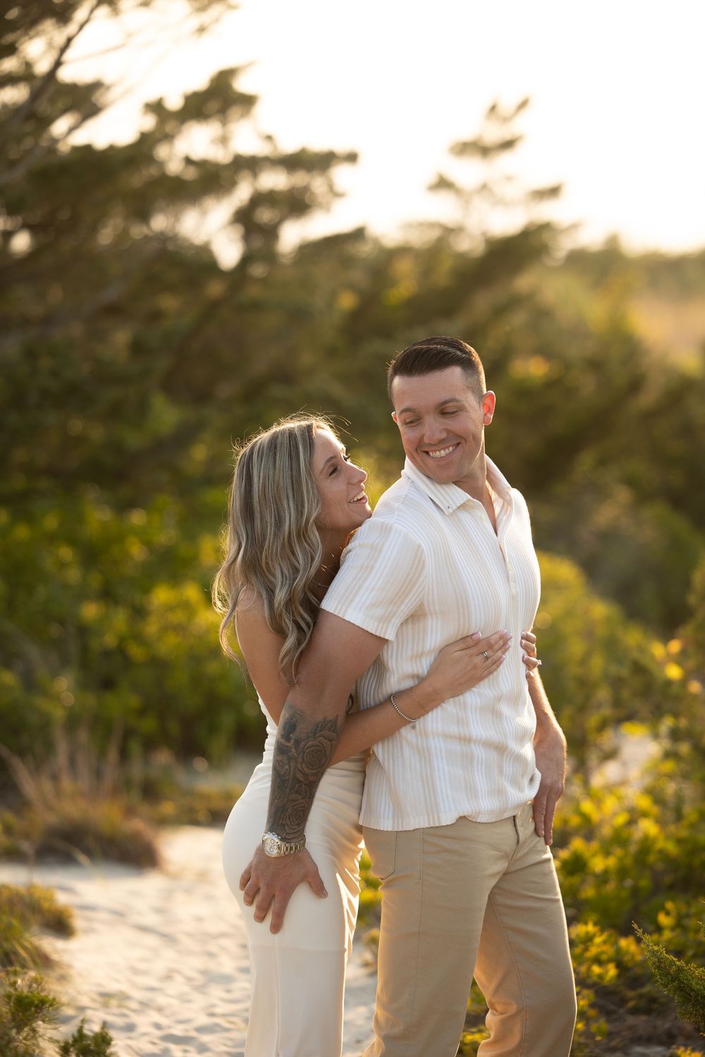 A couple sharing a romantic moment at sunset on a beach with yellow wildflowers in the background.