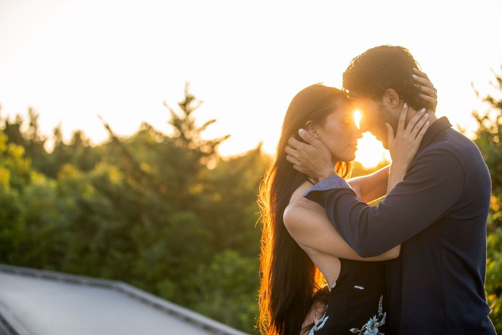 Romantic couple embracing in warm sunset light with evergreen trees in background.