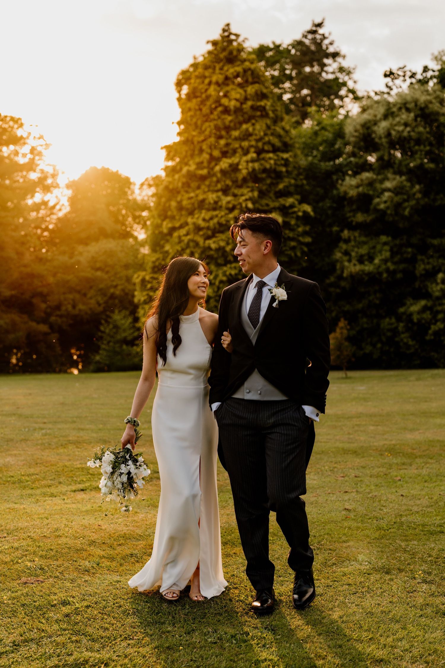 A couple shares intimate moments on their wedding day in a sun-drenched garden during golden hour.