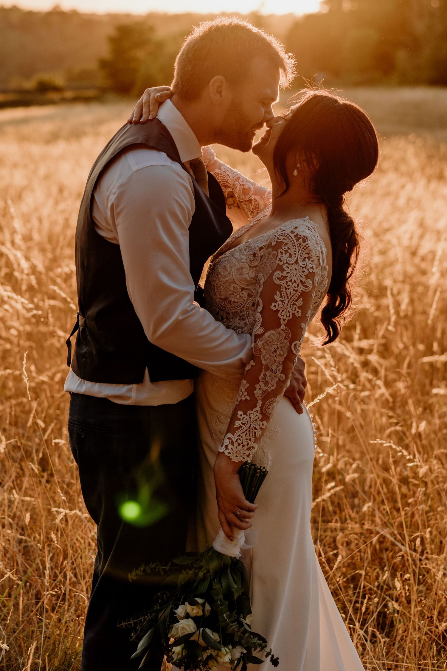A romantic sunset wedding portrait in a golden wheat field with warm backlighting.