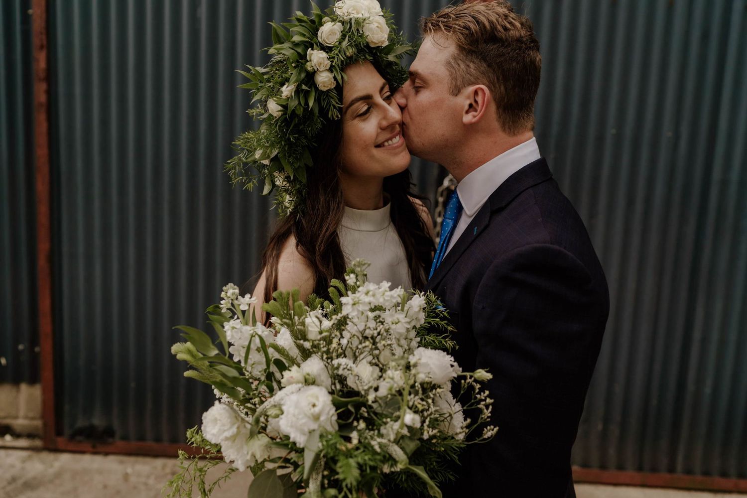 A romantic indoor wedding portrait with white floral decorations and moody lighting.